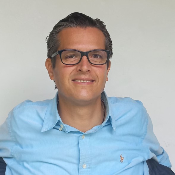 Fotografía de Luis Quintana, vistiendo una camisa azul claro y lentes negros de aumento. 