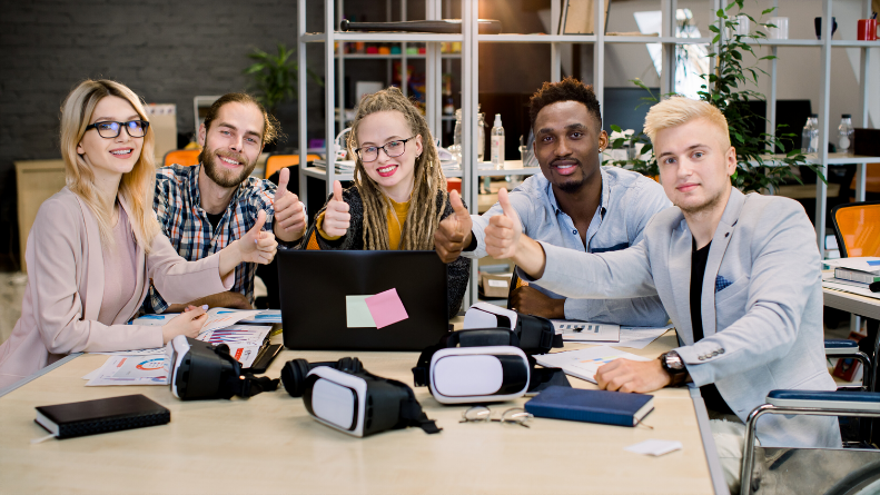 A group of people sitting around a table with a laptop, engaged in collaboration in an indoor office setting.